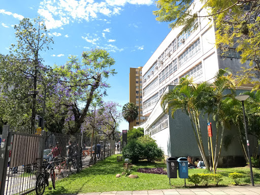 Image of a building in the right side, with green lawn and trees around.