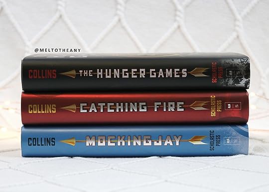 Three books stacked, a black one on top, a red one and a blue one on the bottom.