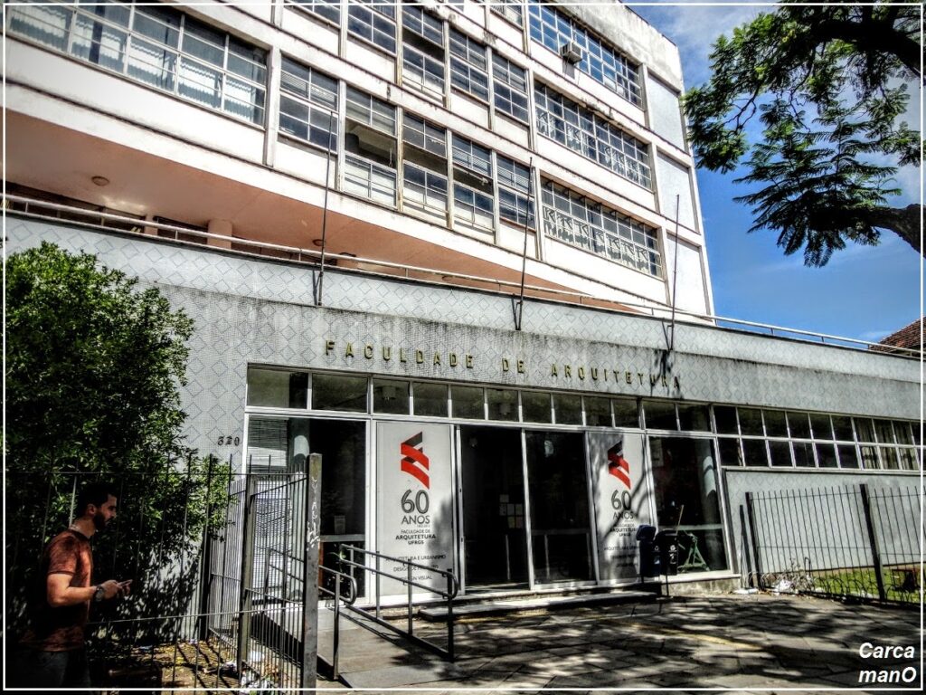 A five-floor building with a glass door and a lot of windows where it says Faculdade de Arquitetura (in portuguese).
